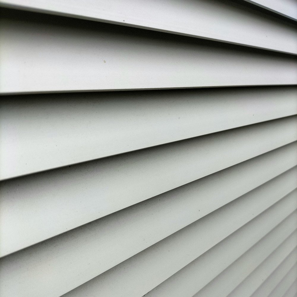 A close-up, angled shot of white horizontal slats or louvers creating a rhythmic pattern of light and shadow.