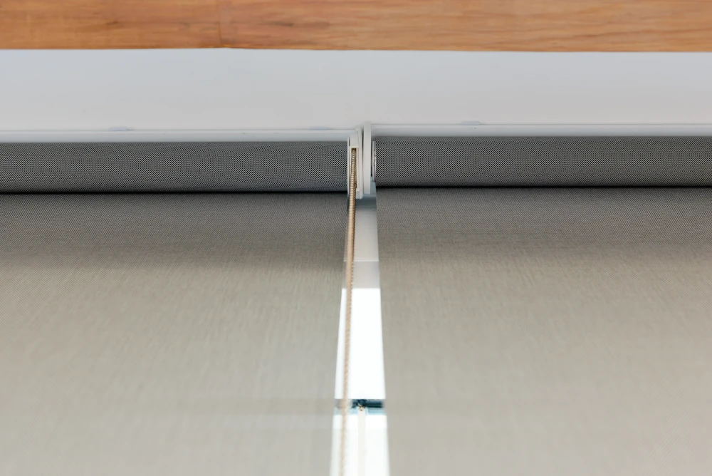 Modern Roller Blind Mechanism Details Close-up view of the mechanism and fabric roll of modern grey roller blinds mounted indoors.